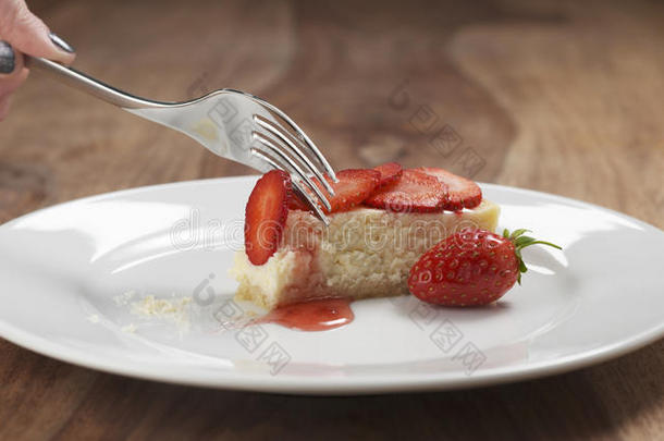 吃<strong>草莓芝士</strong>蛋糕，木桌上有叉子