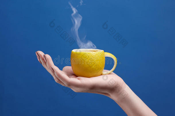柠檬做的茶<strong>杯</strong>。 柠檬<strong>杯</strong>在手，蓝色背景。 天然水果茶主题的<strong>创意</strong>构图