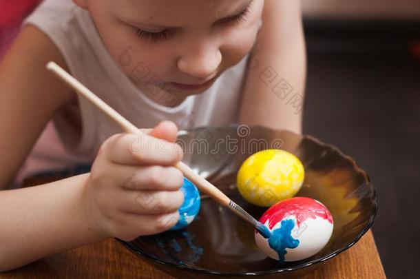 一个小男孩在复活节前夕画鸡蛋，五颜六色的油漆和刷子，