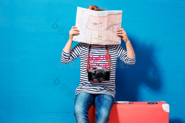 带粉红色老式手提箱和城市地图的金发女孩准备暑假。 旅行和冒险概念