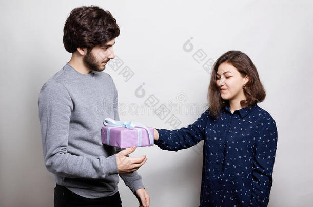 一个快乐的女人从她男朋友那里收到礼物。 一个穿着休闲毛衣的时髦男孩给她女朋友送礼物