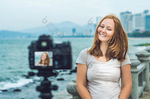 一位年轻的女博主在海边的相机前引导她的视频博客。 博主的概念