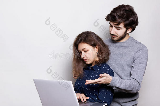 两个使用<strong>笔记本</strong>电脑的年轻人的侧写。 一个漂亮的女孩拿着<strong>笔记本</strong>电脑在网上购物。 年轻的嬉皮士