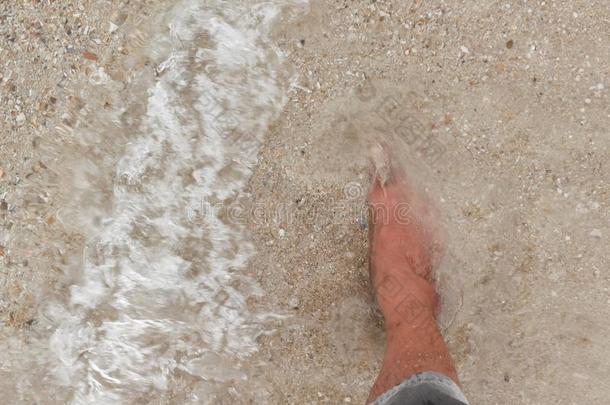 赤脚腿在海滩上散步，在夏天的海上度假