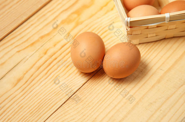 木制桌子背景上篮子里的鸡蛋。