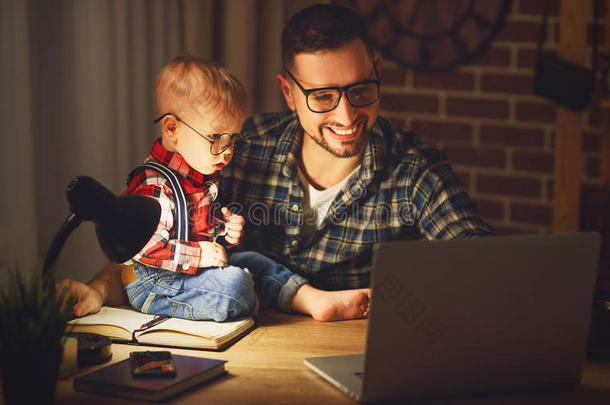 父亲和儿子婴儿在黑暗中在家电脑工作