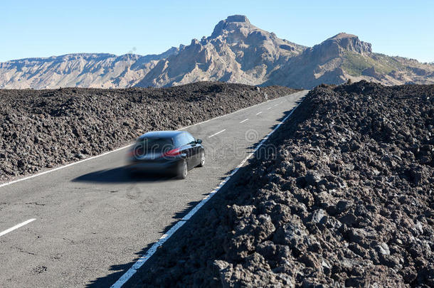 汽车快速驾驶的路线TF-38在火山熔岩卵石中间的沥青路。 加那利，特纳里夫