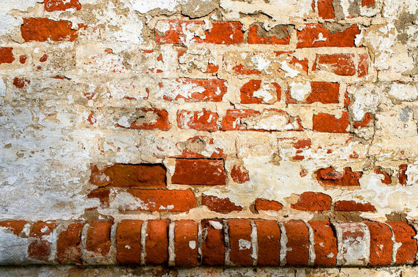 一堵旧的红砖墙，上面有脱落的白色灰泥。