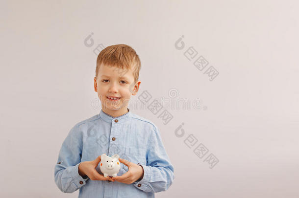 可爱的小男孩拿着储蓄罐或钱箱。 概念儿童和金钱