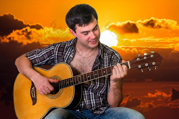 迷人的男人在日落时弹吉他