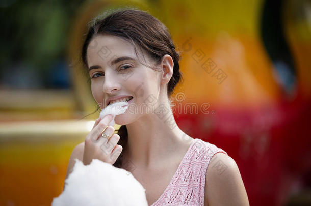 <strong>游乐园</strong>里可爱的白种人女孩正在吃粉红色的糖果。 用棉花糖描绘<strong>快乐</strong>迷人的年轻女人的肖像。