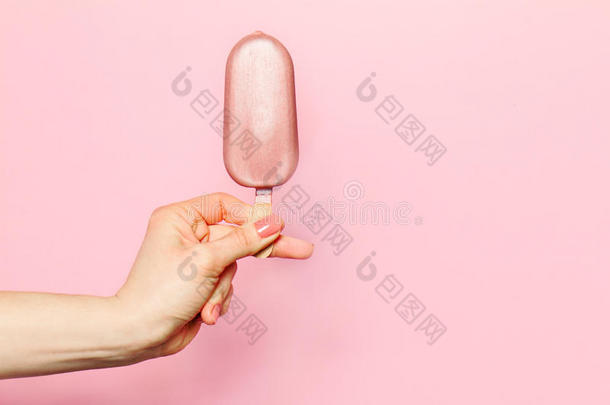 年轻女人的手拿着粉红色背景的冰淇淋。 <strong>时尚背景</strong>。 夏天的概念。