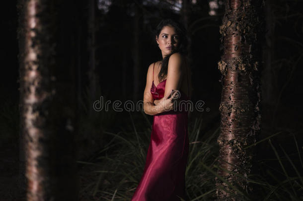 花园里漂亮的年轻女人穿着一件长长的丝绸红色连衣裙。