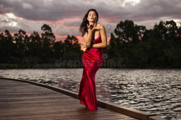 花园里漂亮的年轻女人穿着一件长长的丝绸红色连衣裙。
