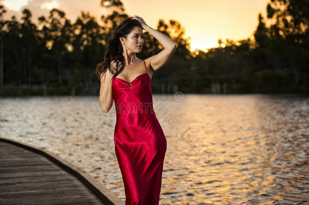 花园里漂亮的年轻女人穿着一件<strong>长长</strong>的丝绸红色连衣裙。