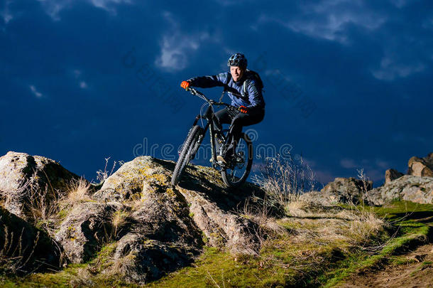 恩杜罗自行车者晚上骑自行车在岩石上。 极限运动概念。 文本的空间。