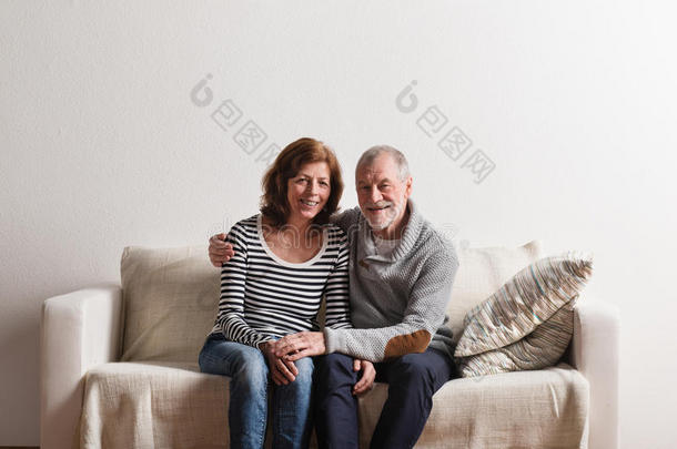 漂亮的老年夫妇<strong>坐</strong>在沙发上<strong>拥</strong>抱。 摄影棚拍摄。