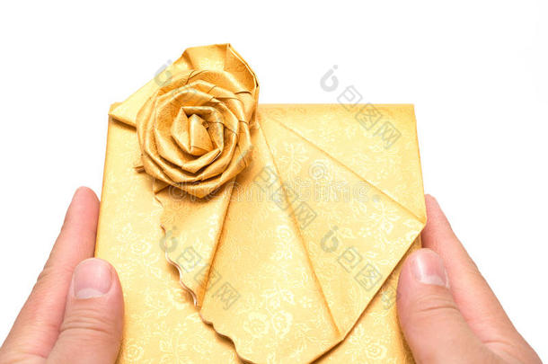 双手拿着一个包裹在白色上的金色礼物盒
