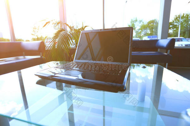 一种现代桌面的桌面，办公室里有一台笔记本电脑在玻璃桌子上