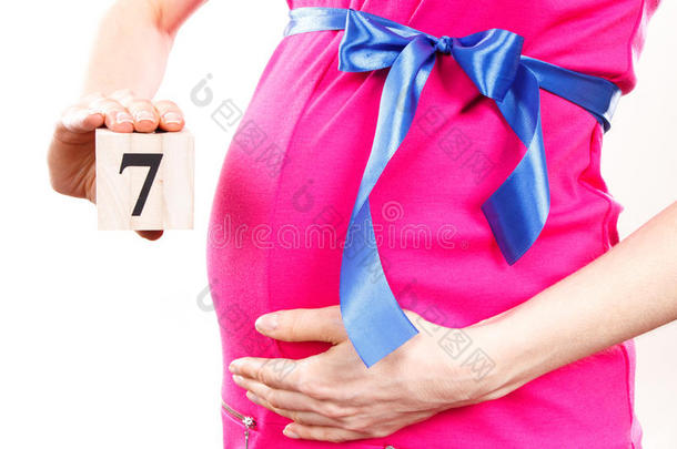 妇女的手显示怀孕第七个月的数量，期待新生儿的概念