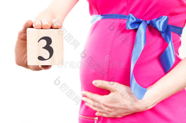 妇女的手显示怀孕第三个月的数量，期待新生儿的概念