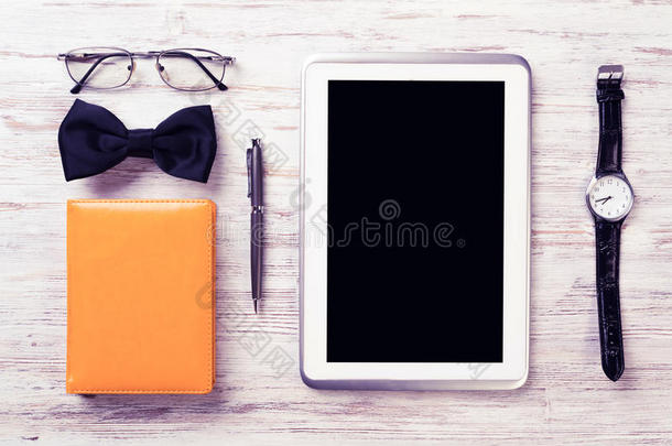绅士套件的平板手表，眼镜，领结和笔记本在木桌上