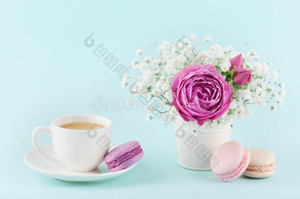 美丽的粉红色玫瑰花和Gypsophilla在花瓶，马卡龙和一杯咖啡在绿松石古董桌子上舒适的早餐。