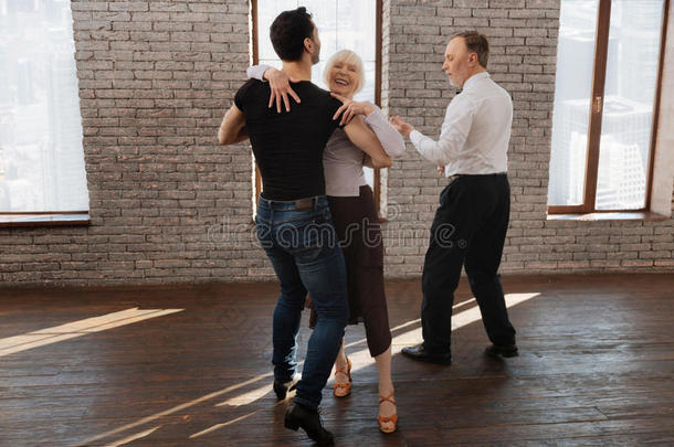 自信的舞蹈教练在舞厅里教老年人华尔兹