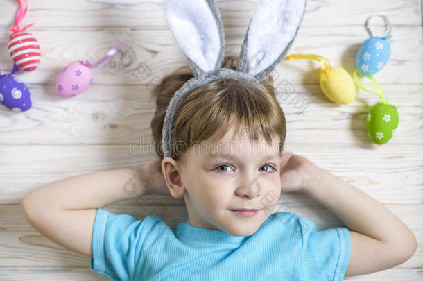 可爱的小男孩在复活节那天在家里抱着一个带着彩色复活节彩蛋的巢。 在春天庆祝复活节。 画鸡蛋