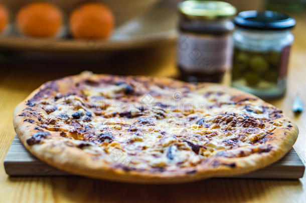 厨房桌子上烤着的自制比萨饼，里面有橄榄和奶酪，一碗水果背景