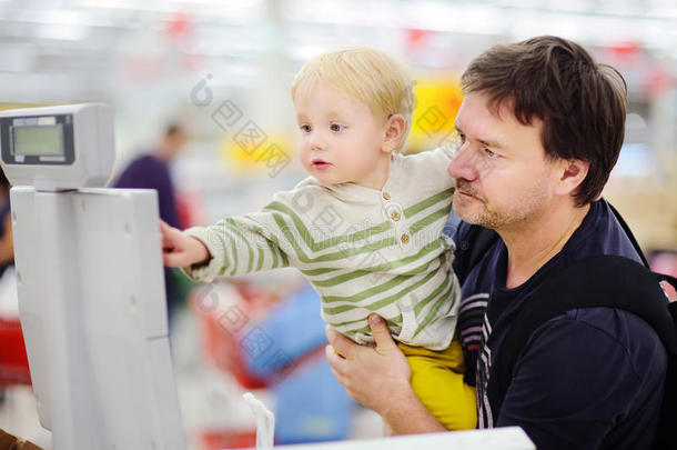 可爱的蹒跚学步的男孩和他的中年父亲在一家食品店或超市