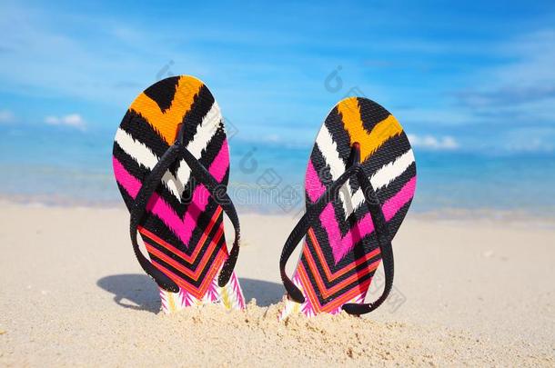 拖鞋。 五颜六色的拖鞋在沙子里。夏天和旅行。