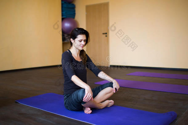 美丽的年轻女人在做瑜伽练习后休息，坐着冥想，闭着眼睛放松。