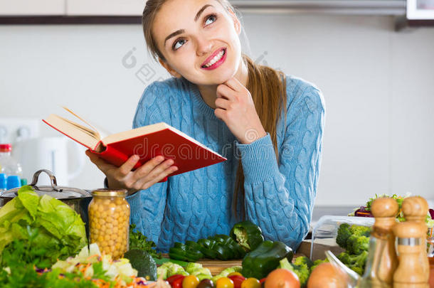 穿套衫的女孩从食谱中学习新的食谱