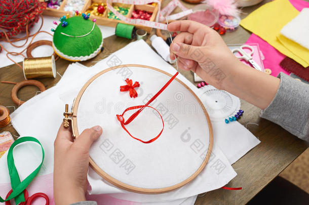 男孩刺绣在箍，手特写和红色丝带在白色纺织品，学习缝纫，工作培训，手工和手工艺公司