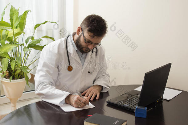 医生<strong>办公室里</strong>的一位穿着白色外套`医生坐在一张桌子旁，在医生`<strong>办公室里</strong>填写文件。