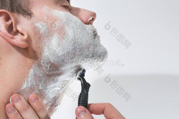 一个年轻人正在刮胡子，刮胡刀刀片，护肤，泡沫，