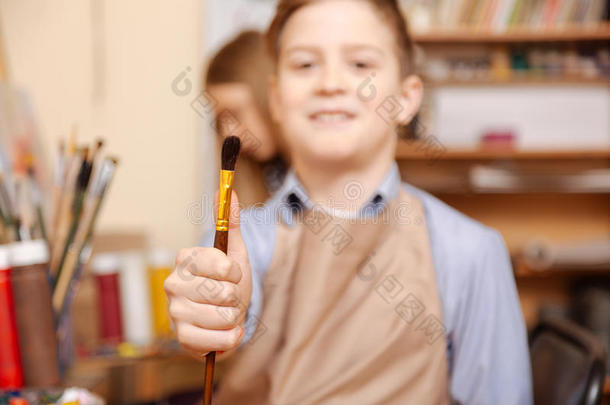 高兴的小男孩在美术课上拿着画笔