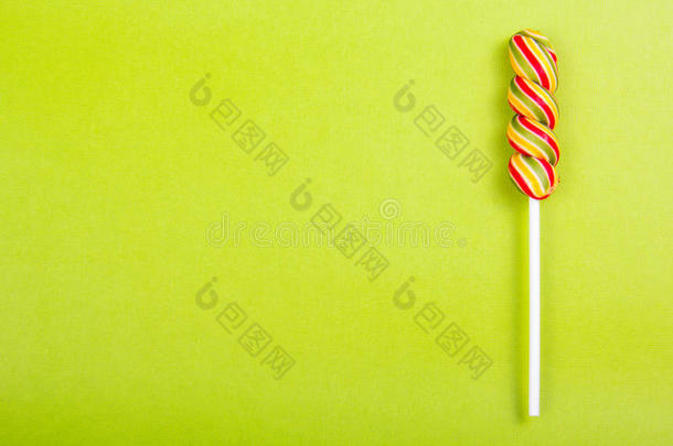 明亮多汁的彩色棒棒糖在绿色背景上。 以彩色螺旋形式出现的棒棒糖。
