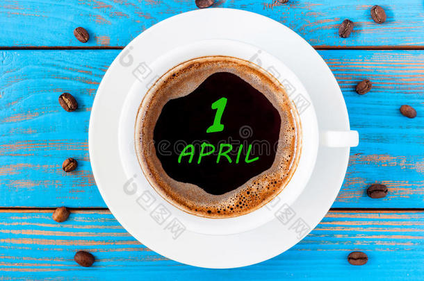 四月一日。 一个月的第一天，日历写在早上的咖啡杯在蓝色的木制背景。 春天的时候，顶景