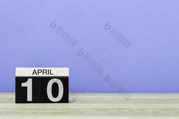 四月十日。 月10日，木桌上的日历和紫色背景。 春天的时间，文字的空空间