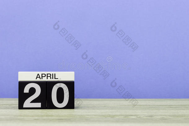 四月二十日。 每月20日，木桌上的日历和紫色背景。 春天的时间，文字的空空间