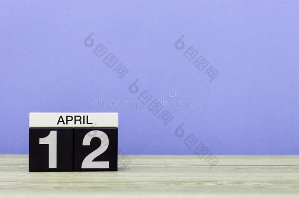 四月十二日。 月12日，木桌上的日历和紫色背景。 春天的时间，文字的空空间