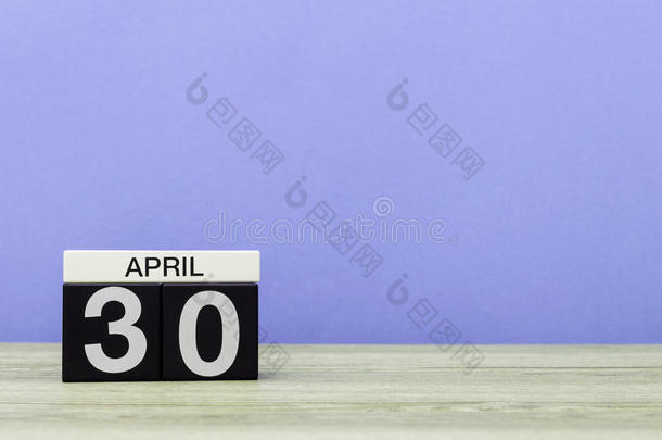 4月30日。<strong>每月</strong>的第30天，木制桌子上的日历和紫色背景。春天，文字空白