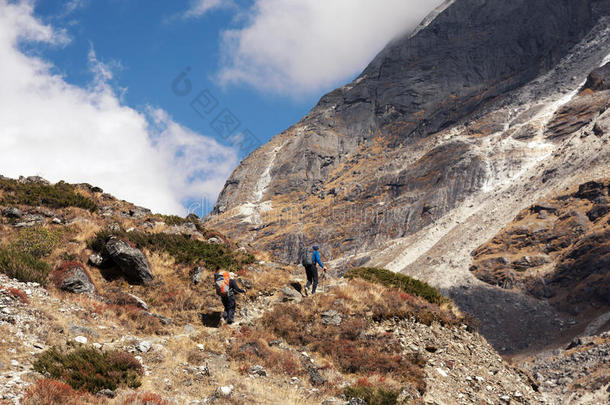 一群徒步旅行者走在山道上朝山口走去