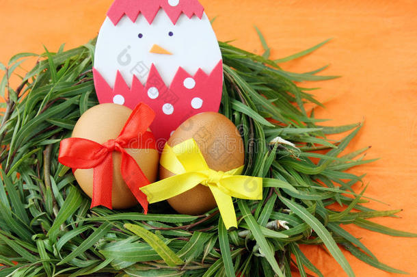复活节装饰：<strong>黄色</strong>的鸡蛋和手工制作的蛋壳中孵化的<strong>小鸡</strong>在绿色的草枝巢在橙色的背景上