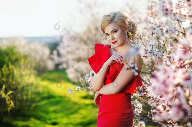 美丽的年轻女人，穿着一件红色的盛开的春天的树