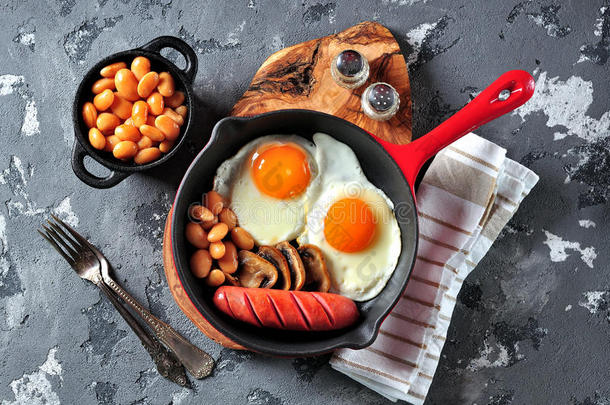 经典的早餐煎鸡蛋，香肠，蘑菇，豆类在铸铁煎锅。
