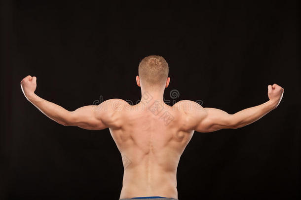 运动帅哥健身模特展示他肌肉发达的背部。 在黑色背景上与copyspace隔离