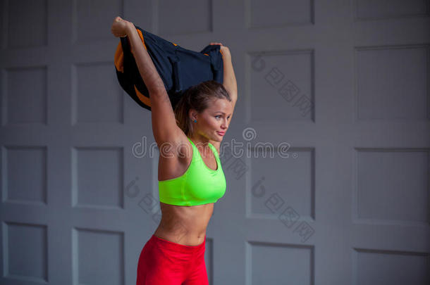 漂亮的年轻女人正在健身房用沙袋训练。